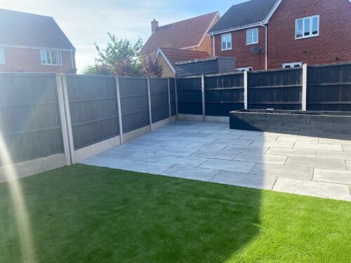 Completed landscaping of back garden in Sudbury, showing new patio, turf and timber planters