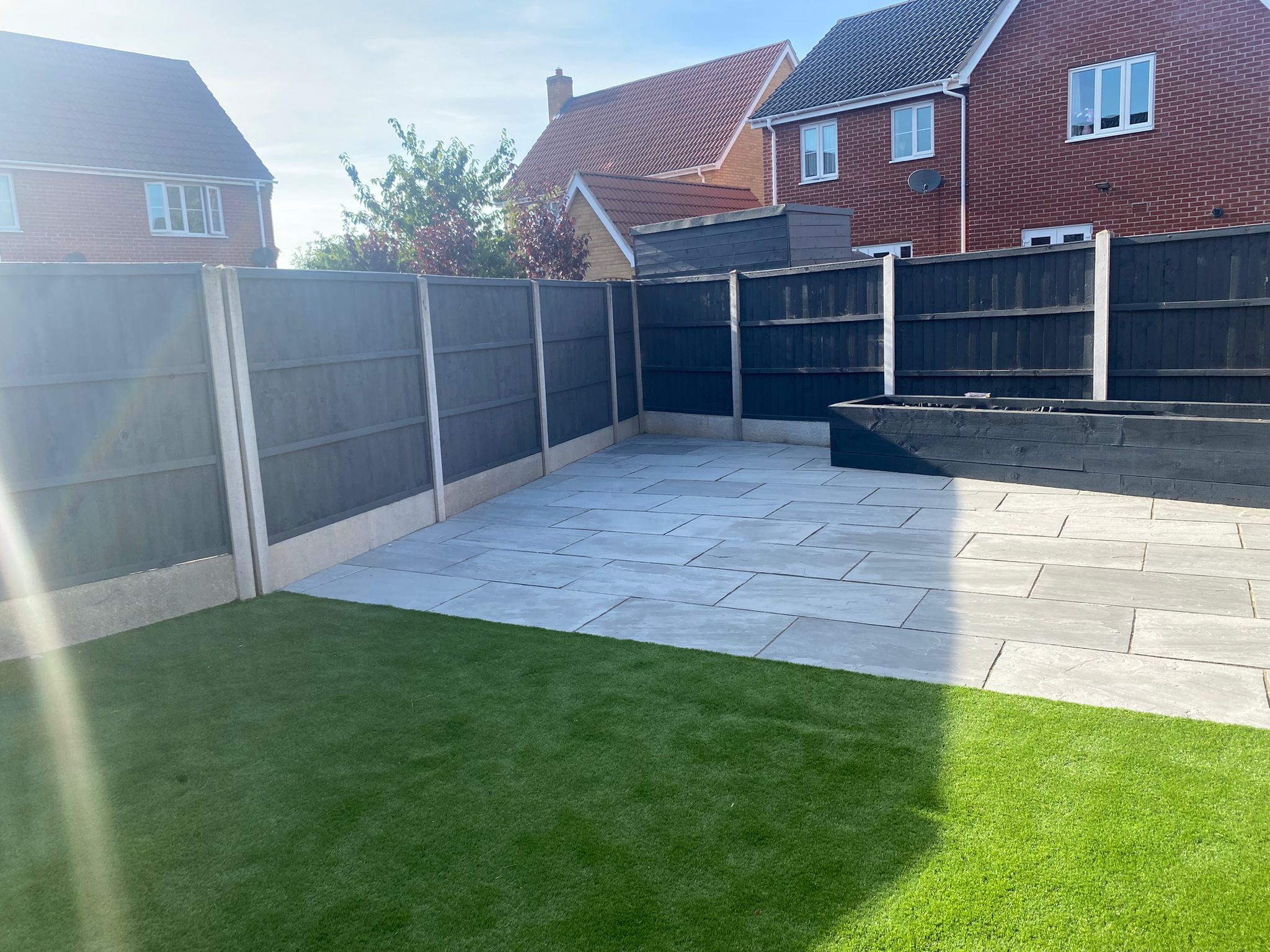 Completed landscaping of back garden in Sudbury, showing new patio, turf and timber planters